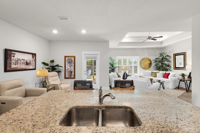 kitchen with light stone counters, open floor plan, and a sink