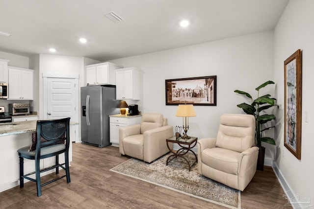 living room featuring a toaster, visible vents, wood finished floors, and recessed lighting