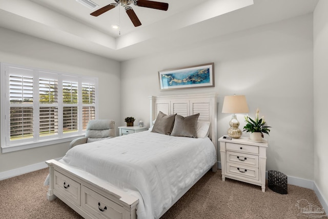 carpeted bedroom with a ceiling fan, visible vents, baseboards, and a raised ceiling