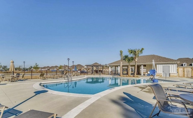 community pool with fence, a patio, and a residential view
