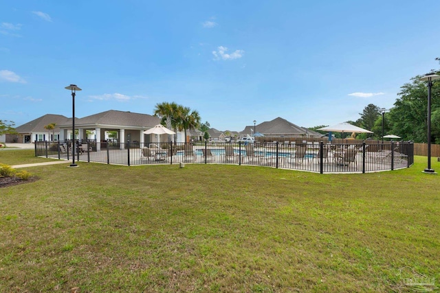 view of property's community featuring a yard, a swimming pool, and fence