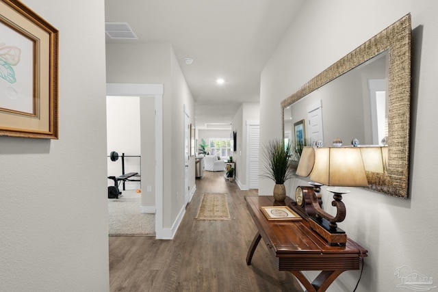 hallway with visible vents, wood finished floors, baseboards, and recessed lighting