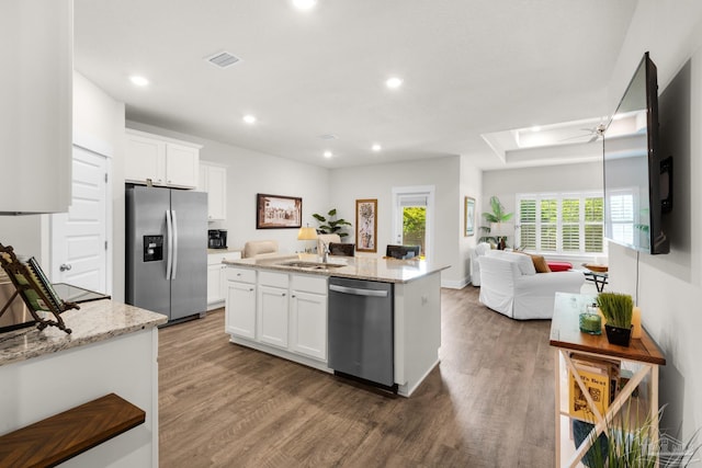 kitchen featuring stainless steel appliances, wood finished floors, open floor plan, and a sink