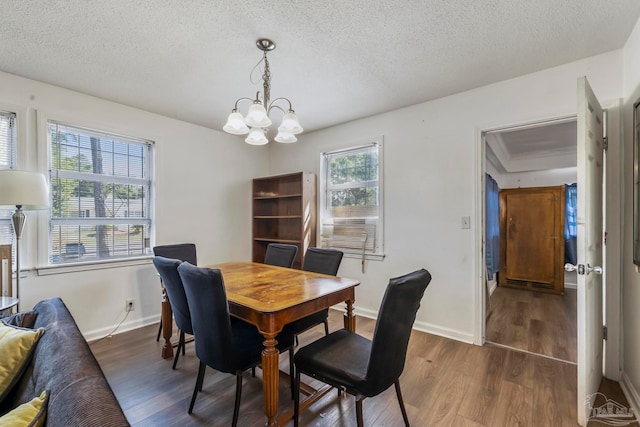 dining room featuring dark wood-type flooring, a textured ceiling, and an inviting chandelier