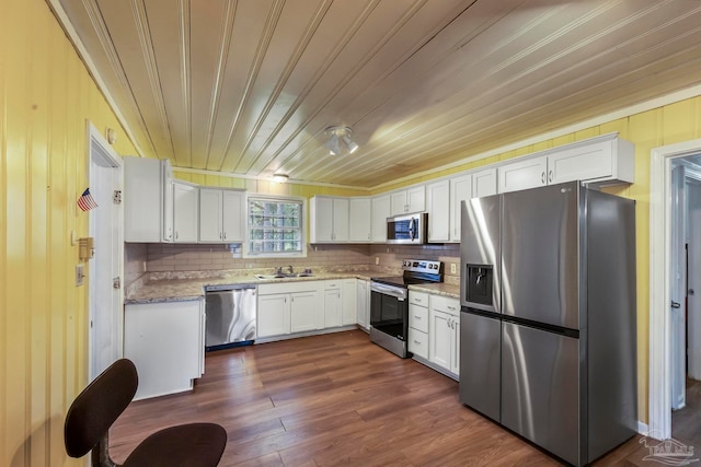 kitchen with appliances with stainless steel finishes, dark wood-type flooring, decorative backsplash, and white cabinets