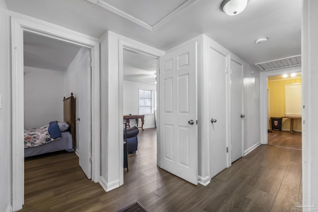 corridor with dark wood-style floors, attic access, visible vents, and baseboards