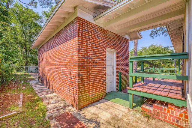 view of property exterior with a wooden deck and brick siding