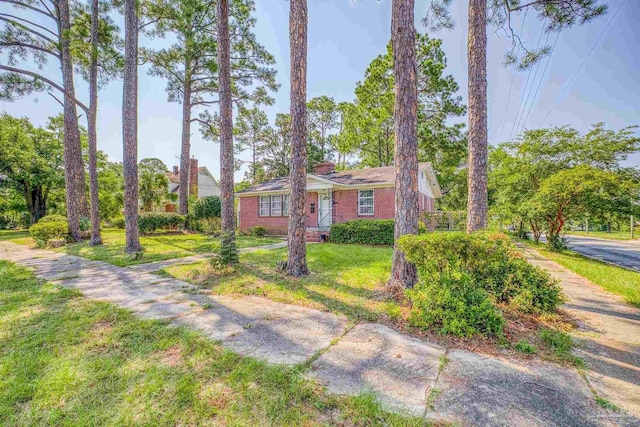 view of front of home featuring a front yard, a chimney, and brick siding