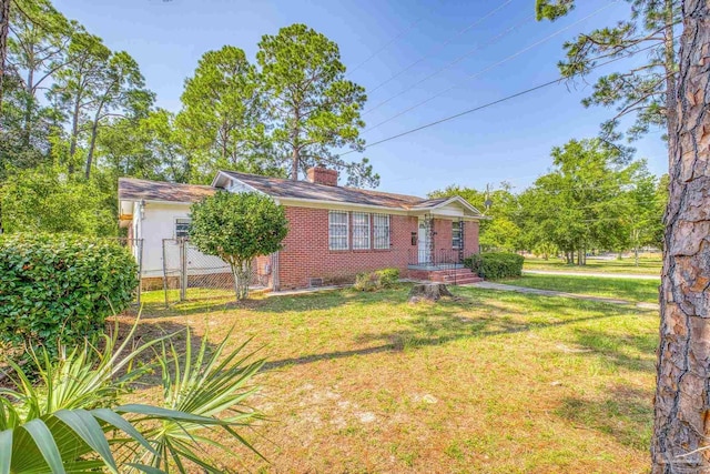 view of front of property featuring brick siding, fence, a chimney, and a front lawn