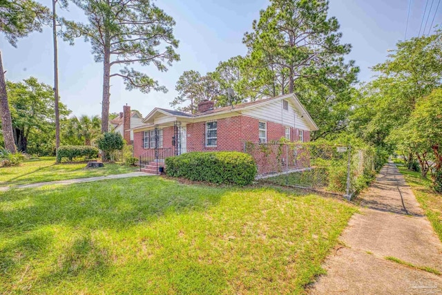 view of front of property featuring a front yard, brick siding, and a chimney