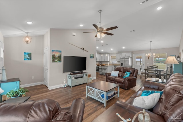 living area with ceiling fan with notable chandelier, vaulted ceiling, recessed lighting, and wood finished floors