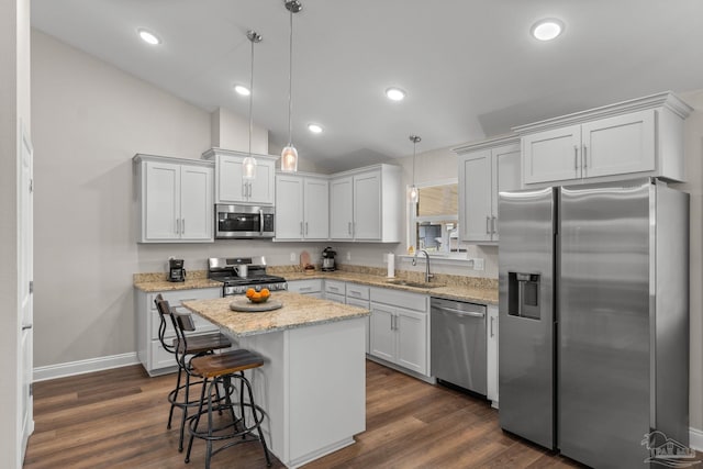 kitchen featuring a kitchen island, appliances with stainless steel finishes, a sink, baseboards, and lofted ceiling