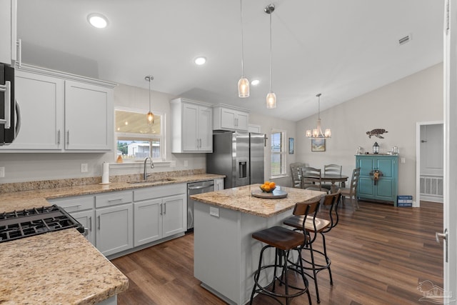 kitchen with a kitchen island, a sink, white cabinets, lofted ceiling, and stainless steel appliances