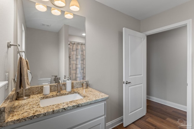 bathroom featuring baseboards, wood finished floors, visible vents, and vanity
