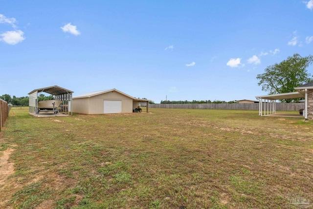 view of yard with fence, an outdoor structure, a detached carport, and a garage