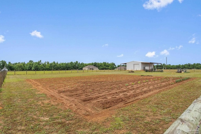 view of community with fence, a rural view, and a garage