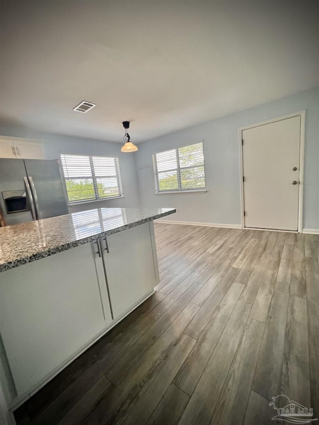 1100 Shoreline Dr Unit 207, Gulf Breeze, FL 32561 - kitchen featuring stainless steel refrigerator with ice dispenser, light stone counters, wood finished floors, white cabinetry, and pendant lighting
