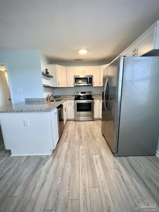 1100 Shoreline Dr Unit 207, Gulf Breeze, FL 32561 - kitchen with appliances with stainless steel finishes, light wood-style floors, light stone countertops, white cabinetry, and open shelves