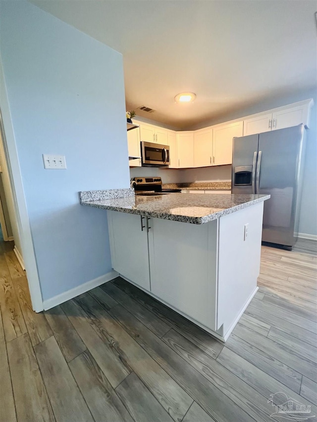 1100 Shoreline Dr Unit 207, Gulf Breeze, FL 32561 - kitchen featuring appliances with stainless steel finishes, wood finished floors, light stone counters, white cabinetry, and a peninsula