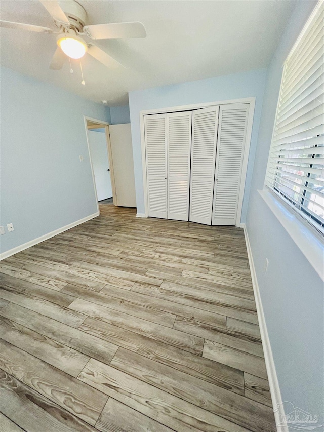 1100 Shoreline Dr Unit 207, Gulf Breeze, FL 32561 - unfurnished bedroom with a closet, wood finished floors, baseboards, and ceiling fan