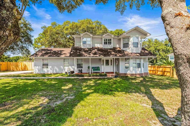 view of front of home featuring covered porch, a front yard, and fence