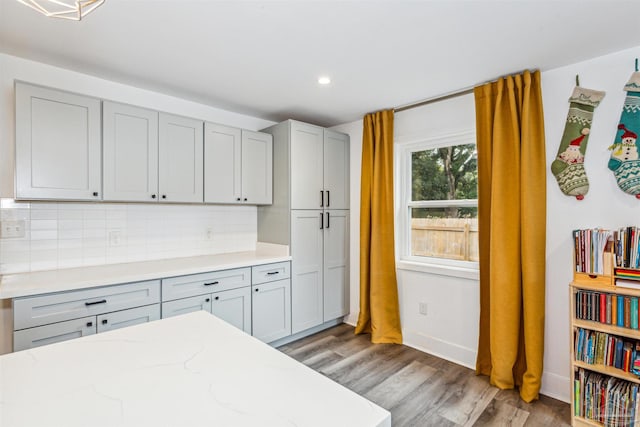 kitchen featuring decorative backsplash, gray cabinets, light stone countertops, and light hardwood / wood-style floors