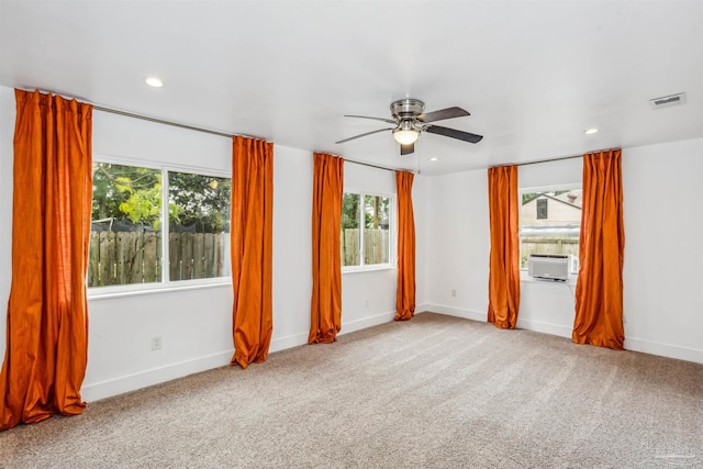 carpeted spare room featuring plenty of natural light and ceiling fan