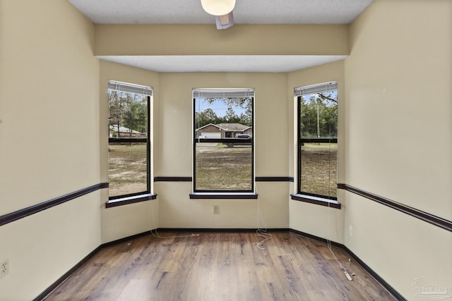 unfurnished room featuring a wealth of natural light, baseboards, and wood finished floors