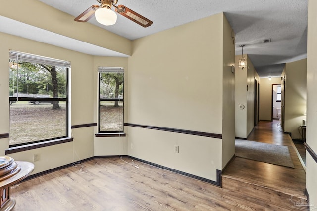 empty room featuring baseboards, a textured ceiling, and wood finished floors