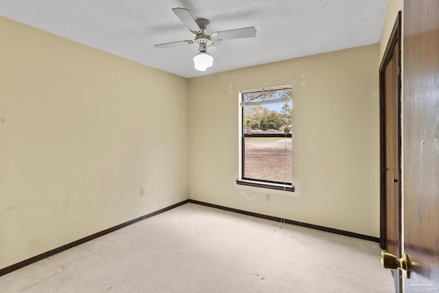 spare room featuring baseboards, light colored carpet, ceiling fan, and a textured ceiling