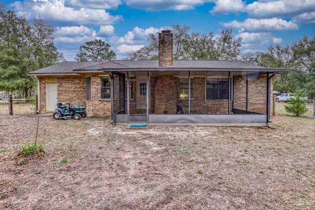 back of property featuring fence, brick siding, a chimney, and a sunroom