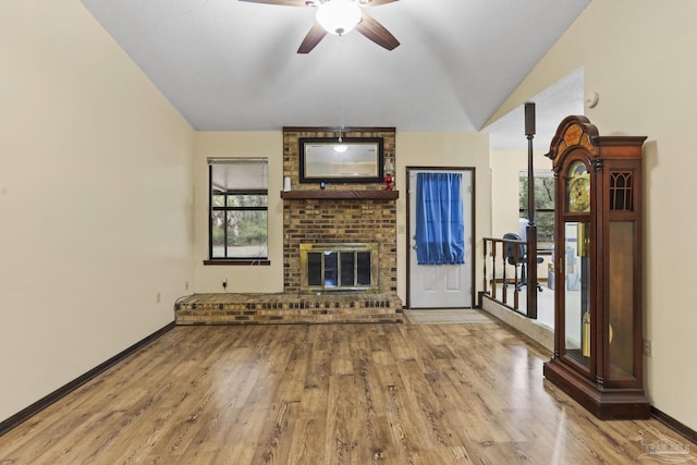 unfurnished living room with baseboards, lofted ceiling, wood finished floors, and a fireplace