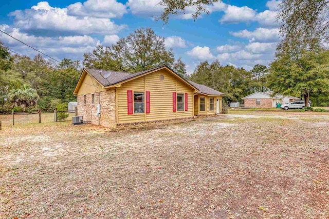 view of front of home featuring cooling unit, brick siding, and fence