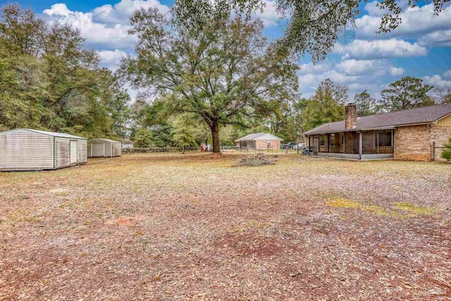 view of yard featuring a storage unit, a sunroom, an outdoor structure, and fence