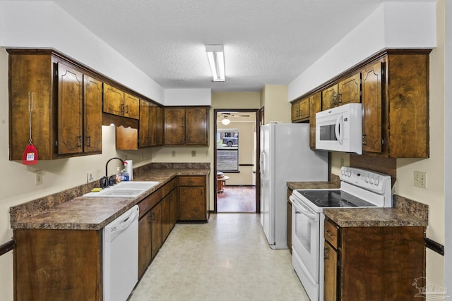 kitchen featuring white appliances, light floors, a sink, a textured ceiling, and dark countertops