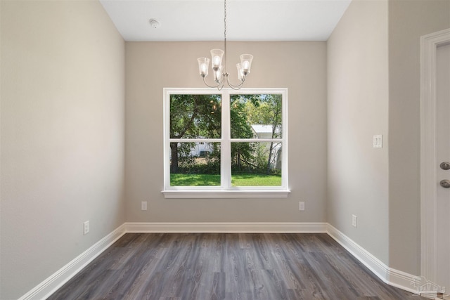 unfurnished dining area with dark wood-type flooring and a notable chandelier