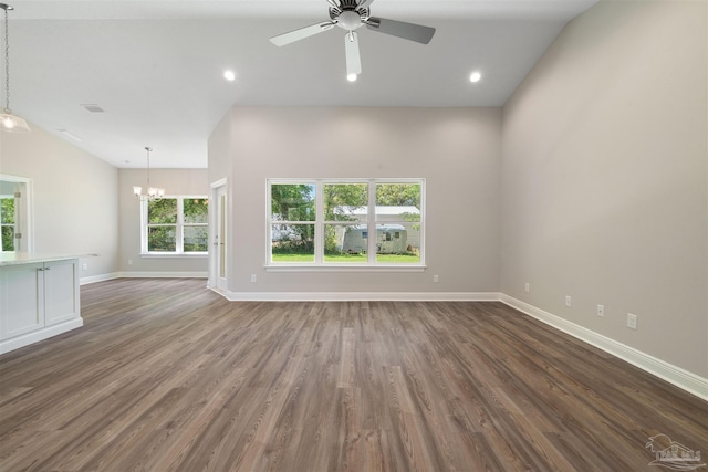 unfurnished living room featuring ceiling fan with notable chandelier, dark wood-type flooring, and vaulted ceiling