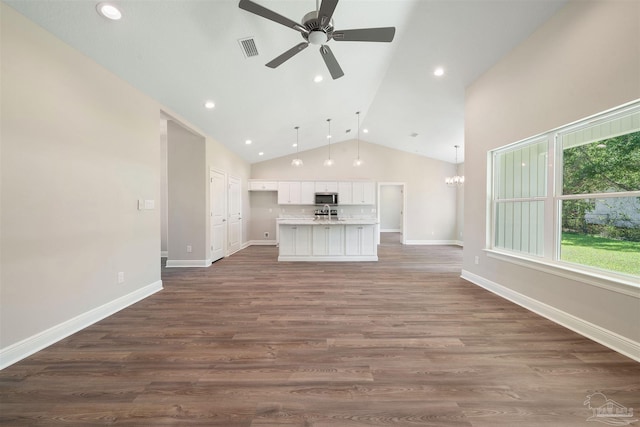 unfurnished living room with dark hardwood / wood-style flooring, high vaulted ceiling, and ceiling fan with notable chandelier