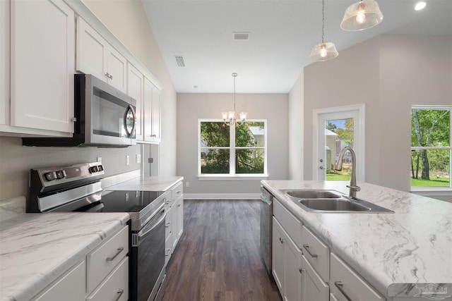 kitchen with a center island with sink, hanging light fixtures, sink, appliances with stainless steel finishes, and white cabinetry