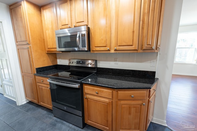 kitchen featuring dark stone countertops, dark hardwood / wood-style flooring, backsplash, and appliances with stainless steel finishes