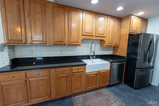 kitchen with dark stone countertops, sink, dark tile patterned flooring, and appliances with stainless steel finishes