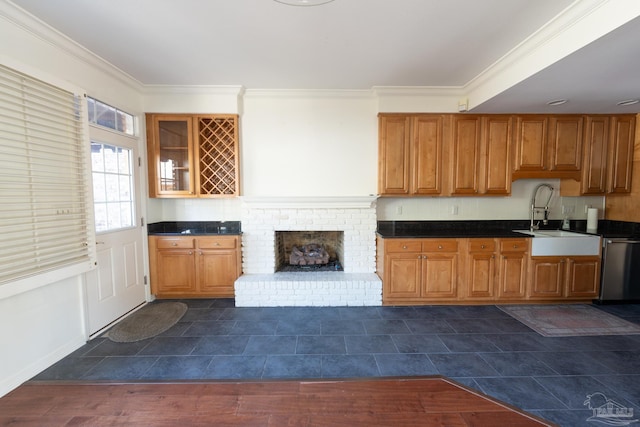 kitchen featuring dishwasher, sink, crown molding, and a brick fireplace