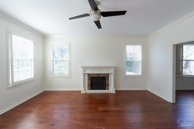 unfurnished living room featuring crown molding, ceiling fan, dark wood-type flooring, and a tiled fireplace