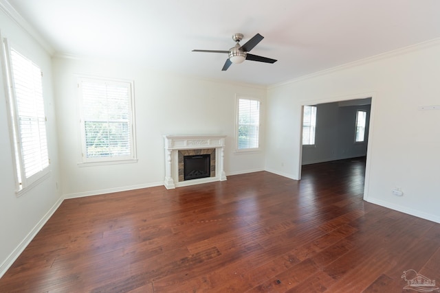 unfurnished living room with a fireplace, dark wood-type flooring, crown molding, and a healthy amount of sunlight