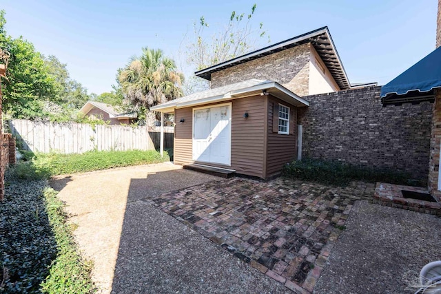 rear view of property featuring an outbuilding and a patio area