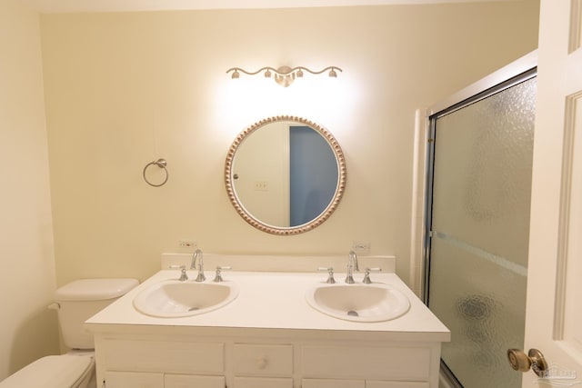 bathroom featuring a shower with door, vanity, and toilet