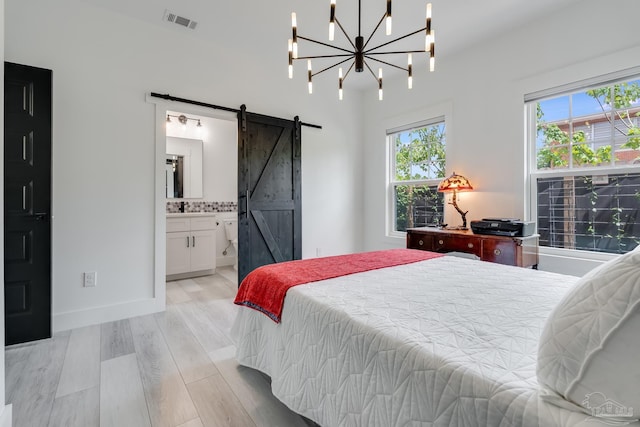 1132 N I St, Pensacola, FL 32501 - bedroom featuring a barn door, light wood finished floors, ensuite bath, and a chandelier