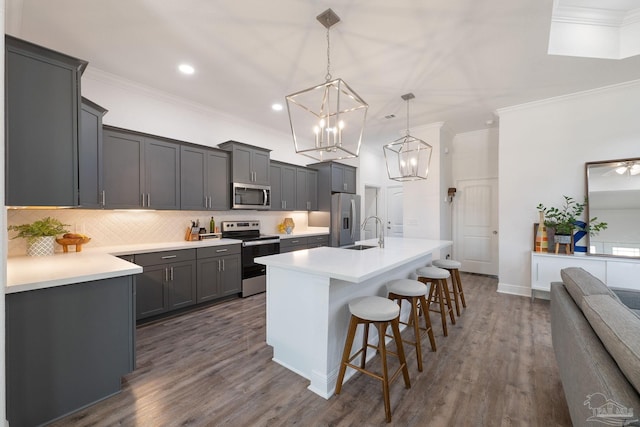 kitchen with decorative backsplash, a kitchen bar, a sink, a notable chandelier, and stainless steel appliances