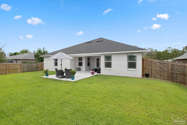 rear view of property with brick siding, a patio, a yard, and a fenced backyard