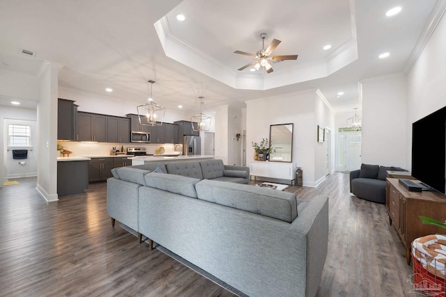 living room with recessed lighting, ornamental molding, ceiling fan with notable chandelier, and dark wood-type flooring
